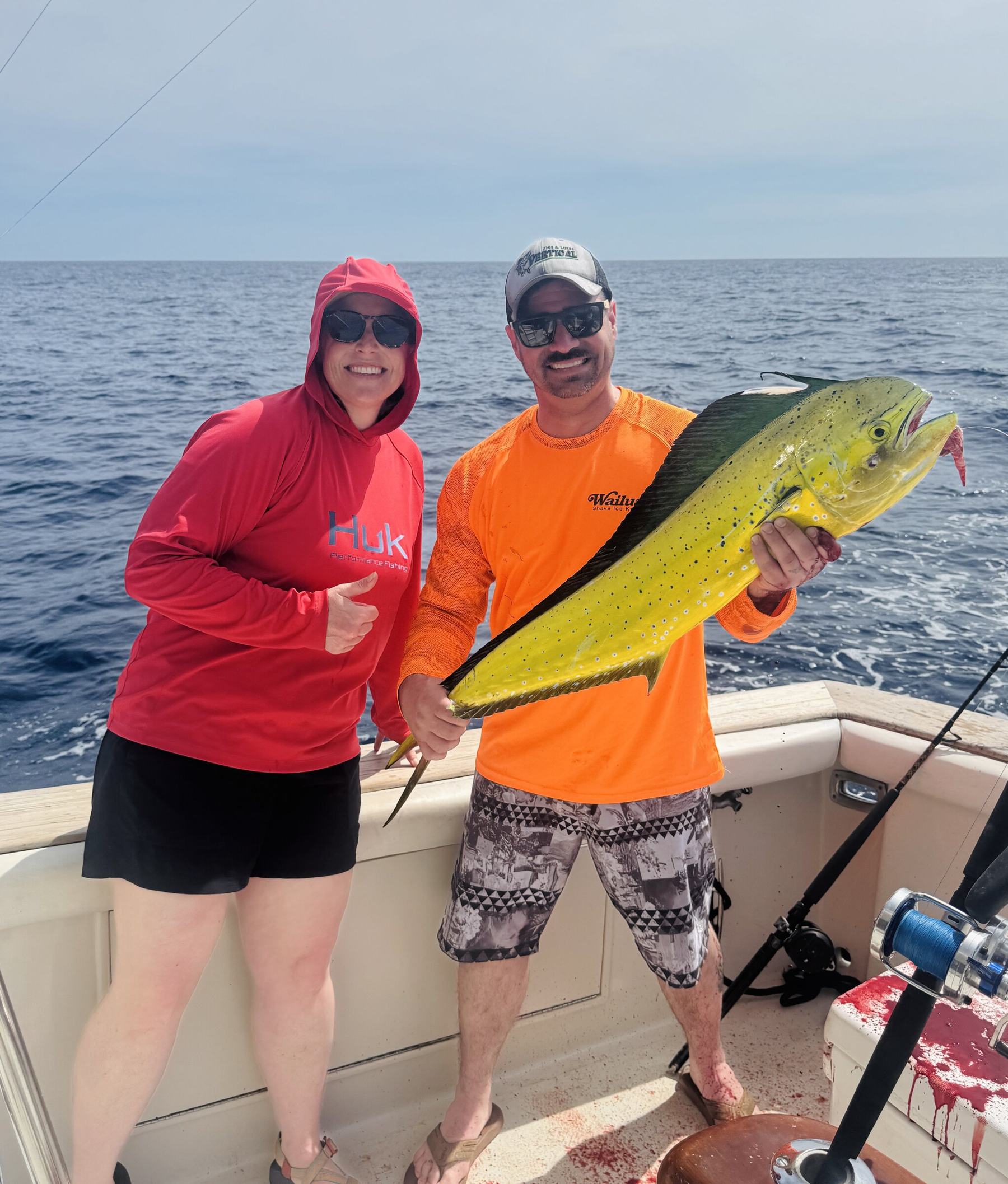 Two anglers holding a mahi-mahi on the boat